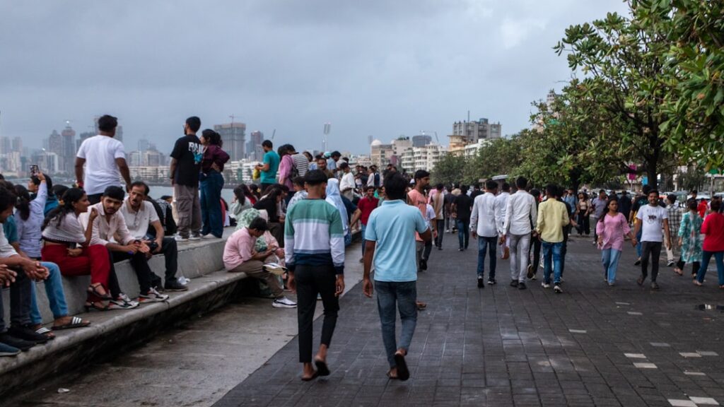People stroll along a boardwalk by the water.